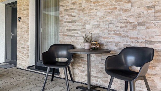 A modern outdoor seating area with two black chairs, a small round table, and a potted plant. - Studio 'Rebstock' with Wi-Fi (Herbolzheim)