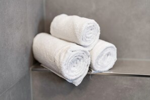 Three rolled white towels stacked on a metallic surface.