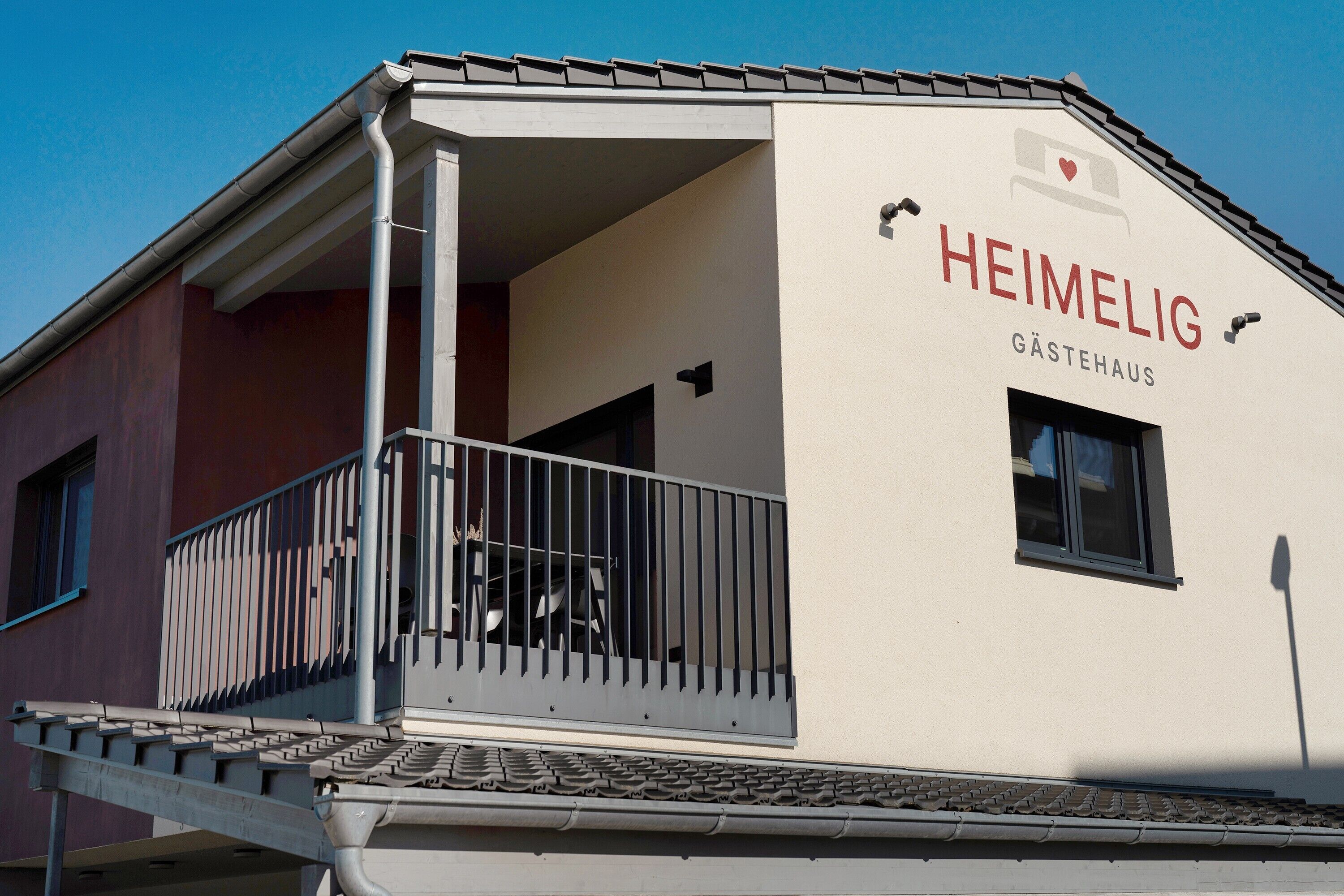 A building with a balcony and a sign reading 'HEIMELIG GÄSTEHAUS.'