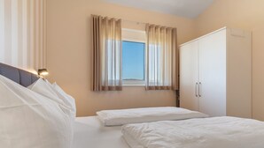 A bedroom with a bed, a wardrobe, a window with curtains, and a headboard.