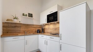 A modern kitchen with white cabinets, a wooden countertop, and a built-in microwave.