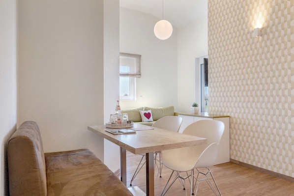 Un espace repas moderne avec une table en bois, des chaises blanches et un banc.