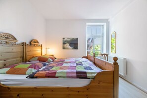 Een slaapkamer met een houten bed, een dressoir, een raam met uitzicht en een ingelijst schilderij aan de muur.
