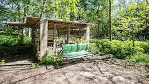 Una estructura de madera con un banco, rodeada de árboles.
