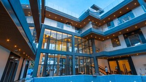 Un edifici modern amb diverses plantes, grans finestres de vidre i un atrium central.