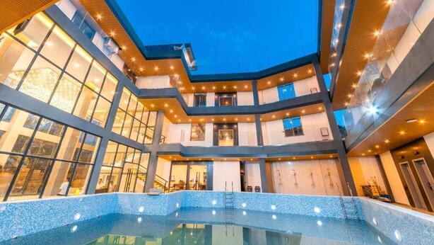 Un edifici modern amb una piscina central, múltiples plantes i grans finestres.