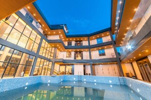 A modern building with a central pool, multiple floors, and large windows. - Begonia resort (Panglao)