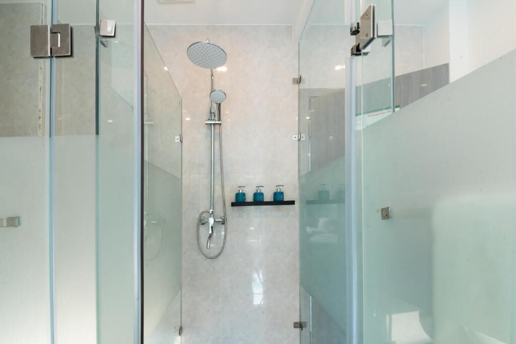 A modern bathroom with a glass shower enclosure, a handheld showerhead, and a wall-mounted faucet.