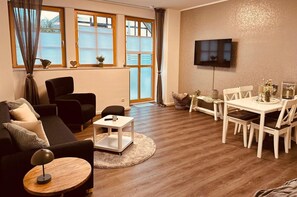 A living room with a sofa, coffee table, TV, and dining area with chairs and a table. - Apartment 'Lütten Ankerplatz' with Private Terrace and Wi-Fi (Eggesin)