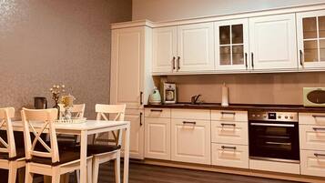 Una cocina con armarios blancos, una mesa de comedor con sillas y un microondas.