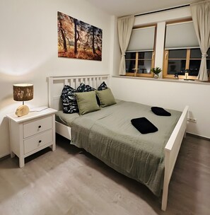 Ein Schlafzimmer mit Bett, Nachttisch, Lampe und einem Bild an der Wand.