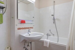 Een badkamer met een witte wastafel, een spiegel, een douche en een handdoekhouder.