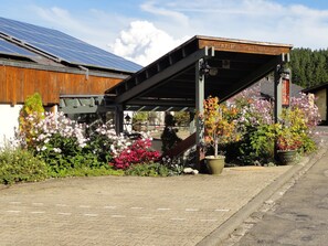 Um edifício com fachada de madeira, área externa coberta com plantas em vasos e painéis solares no telhado.