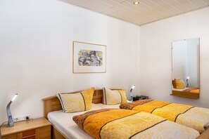 Een hotelkamer met een bed, nachtkastje, lamp en een kunstwerk in een lijst aan de muur.