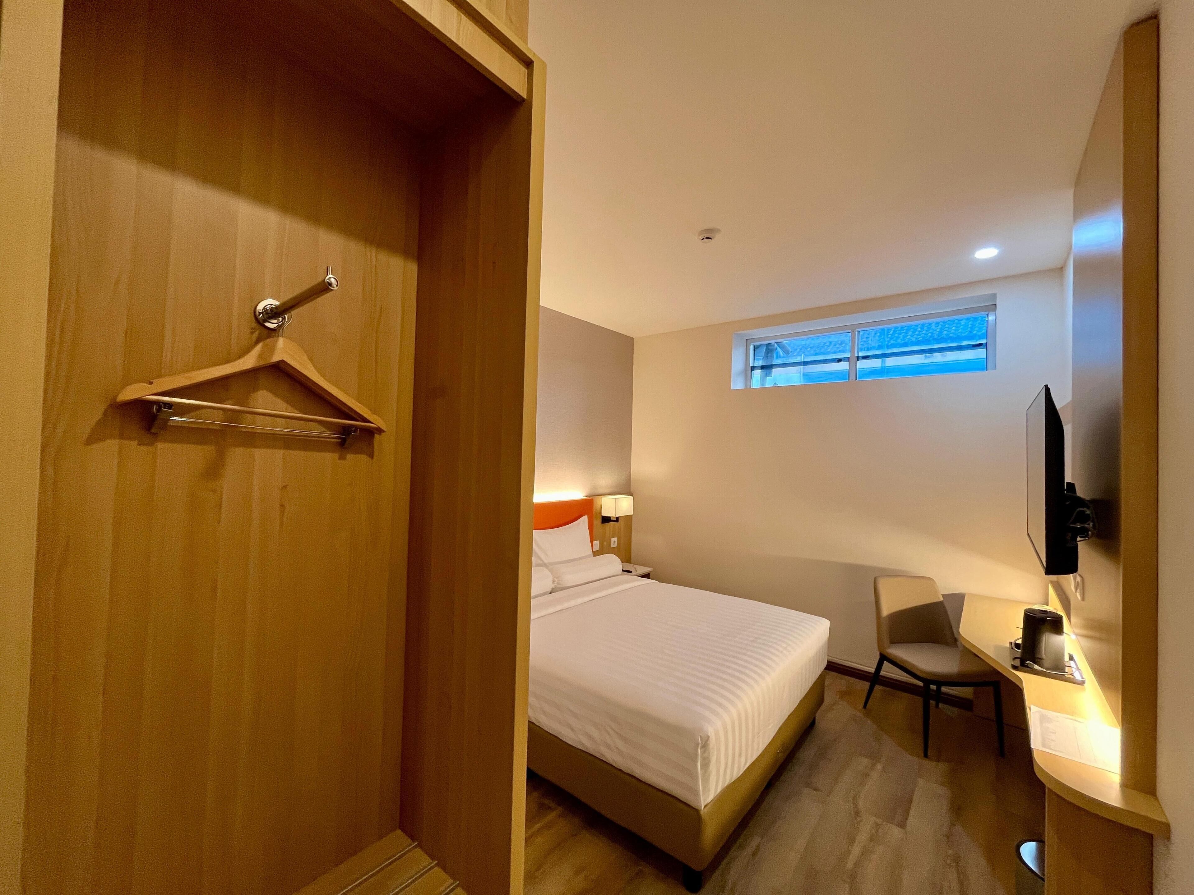 Una habitación de hotel con una cama, un escritorio, una silla, un televisor y una ventana.