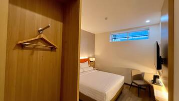 Una habitación de hotel con una cama, un escritorio, una silla, un televisor y una ventana.