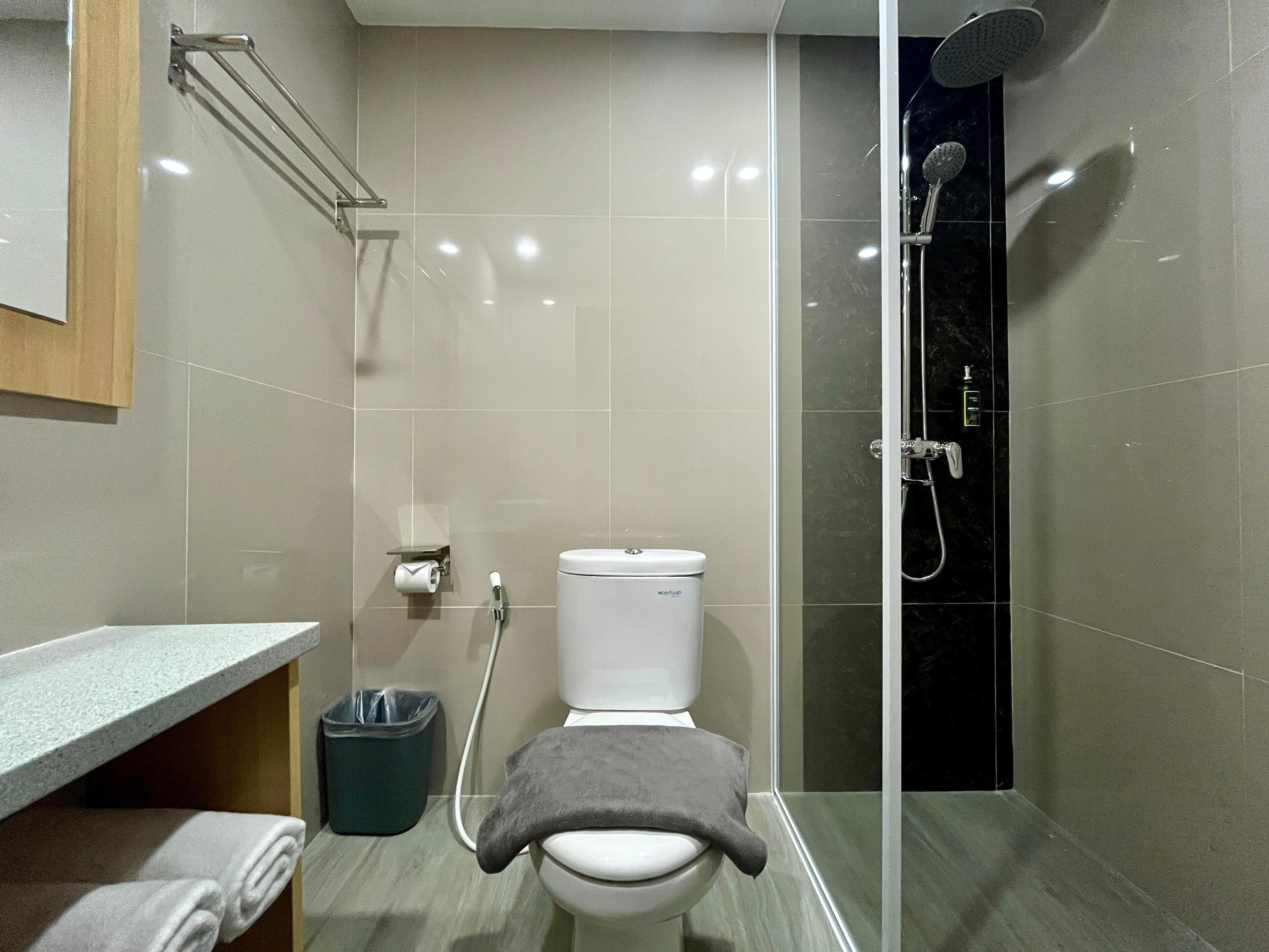 A modern bathroom with a toilet, shower, and a towel rack.
