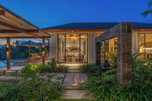 Ein modernes Haus mit Glastür, Schwimmbad und Sitzgelegenheiten im Freien.