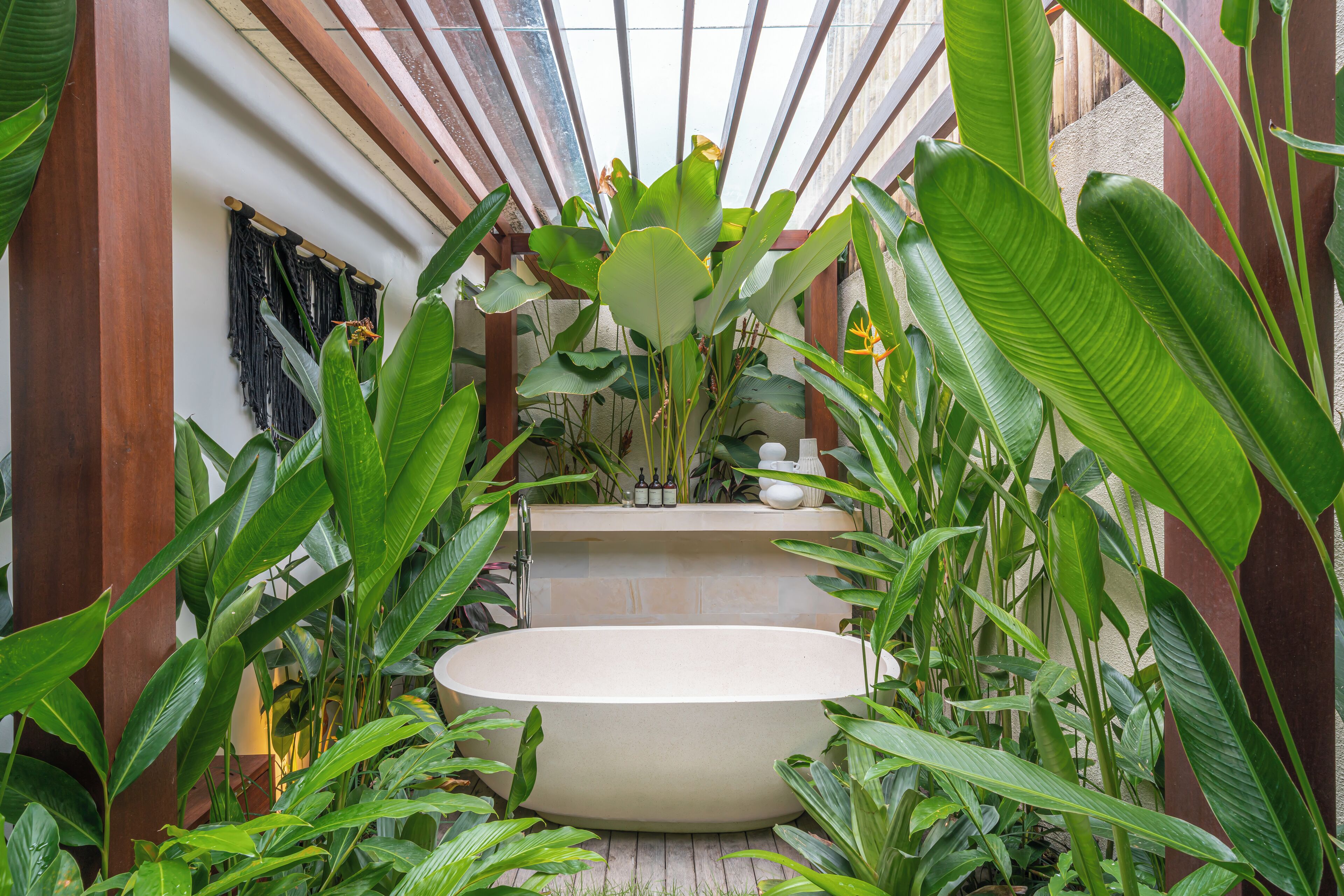 A spa area with a freestanding bathtub surrounded by lush tropical plants.