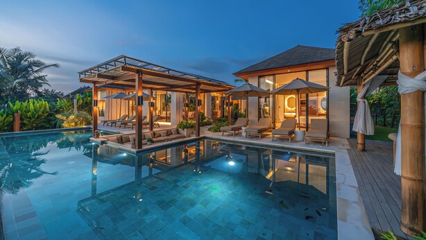A luxurious poolside area with a glass-enclosed lounge, outdoor seating, and a well-lit patio. - Rosita Ubud - Stunning 5BR Villa  (Ubud)