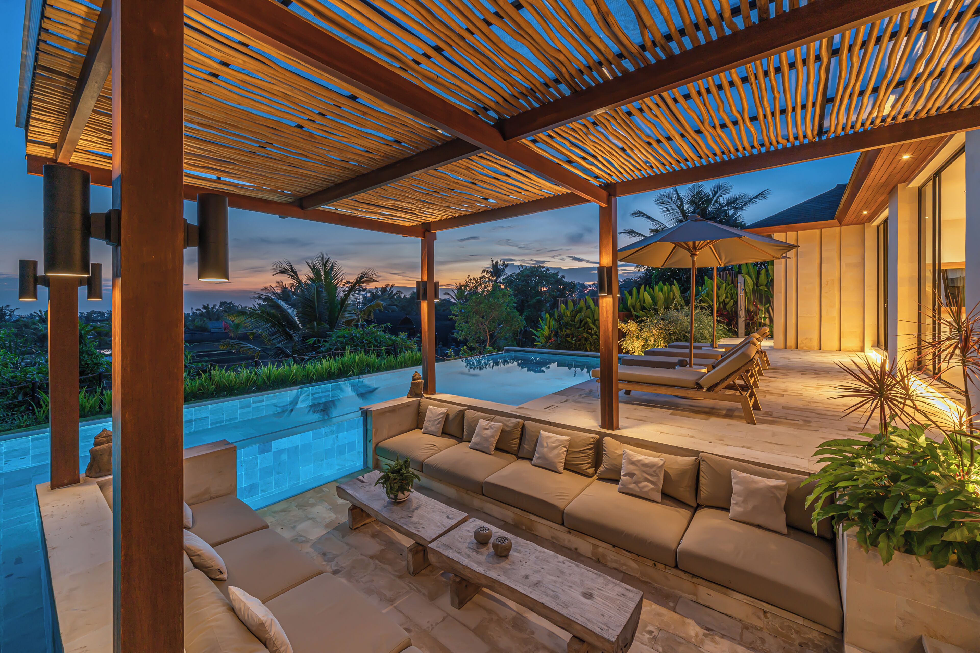 A covered outdoor seating area with a pool, wooden pergola, and a view of the surrounding landscape.