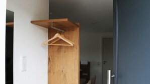 Un pasillo con un armario de madera, un perchero, un comedor con sillas y una puerta azul.