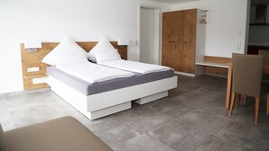 Un dormitorio moderno con una cama, cabecera de madera, un escritorio y un armario.