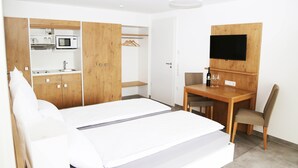 A hotel room with a bed, a desk with a chair, a TV mounted on a wooden panel, a microwave, and a small kitchenette. - Apartment 'Nr 2' with Mountain View, Shared Terrace and Wi-Fi (Vaihingen)