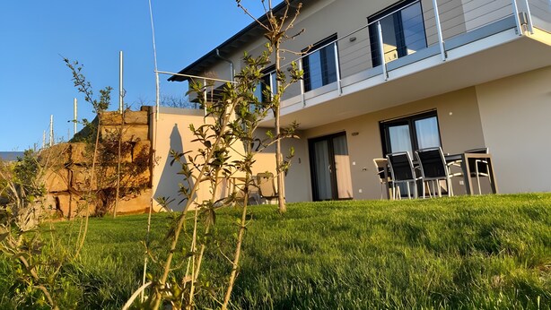 A modern two-story building with a balcony, a grassy yard, and a clear sky. - Apartment 'Nr 2' with Mountain View, Shared Terrace and Wi-Fi (Vaihingen)