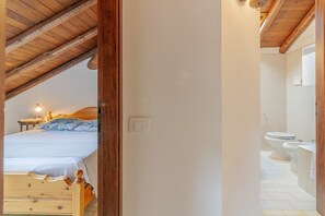 Ein Schlafzimmer mit Holzbalkendecke und einem Bett mit blau-weißer Bettdecke.