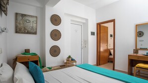 Una habitación de hotel con cama, escritorio, silla, puerta y decoración en las paredes.