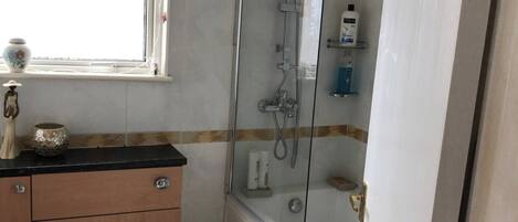 A bathroom with a toilet, a sink, a shower, and a window.