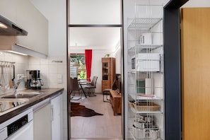 A modern kitchen with a dishwasher, coffee maker, and a dining area with a red curtain.