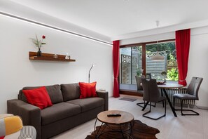 A modern living room with a sofa, a coffee table, and a dining area with chairs.