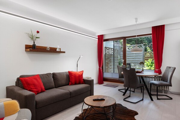 A modern living room with a sofa, a coffee table, and a dining area with chairs. - Apartment '4 Hase, 49qm' with Private Terrace and Wi-Fi (Schönwald im Schwarzwald)