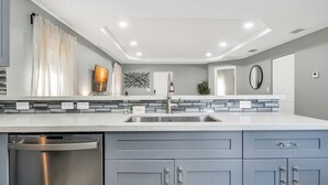 Una cocina moderna con lavavajillas de acero inoxidable, armarios grises y encimera blanca.