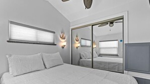 A bedroom with a large bed, a sliding closet door, and two wall-mounted light fixtures. - Luxury 168 Long Island Village (Port Isabel)