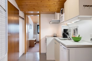 A modern kitchen with white cabinets, a green bowl on the counter, and a wooden ceiling.