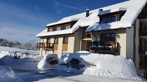 A two-story chalet with a snow-covered roof and a balcony. - Apartment 'No. 3c' with Private Terrace and Wi-Fi (Titisee-Neustadt)