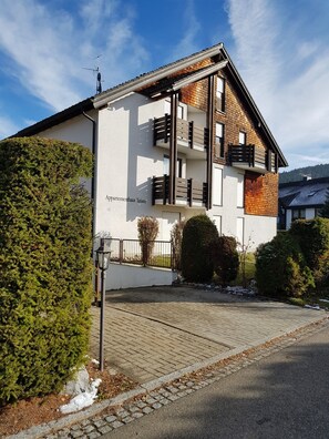 Un bâtiment moderne à deux étages, doté d’un balcon, d’une entrée bien visible et d’un jardin bien entretenu.