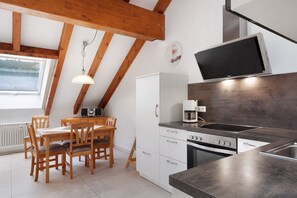 Cucina con tavolo e sedie, una macchina da caffè e una TV montata a parete.