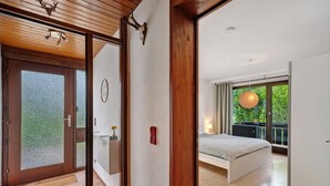 Een moderne slaapkamer met een groot bed, uitzicht op groen buiten en een houten plafond.