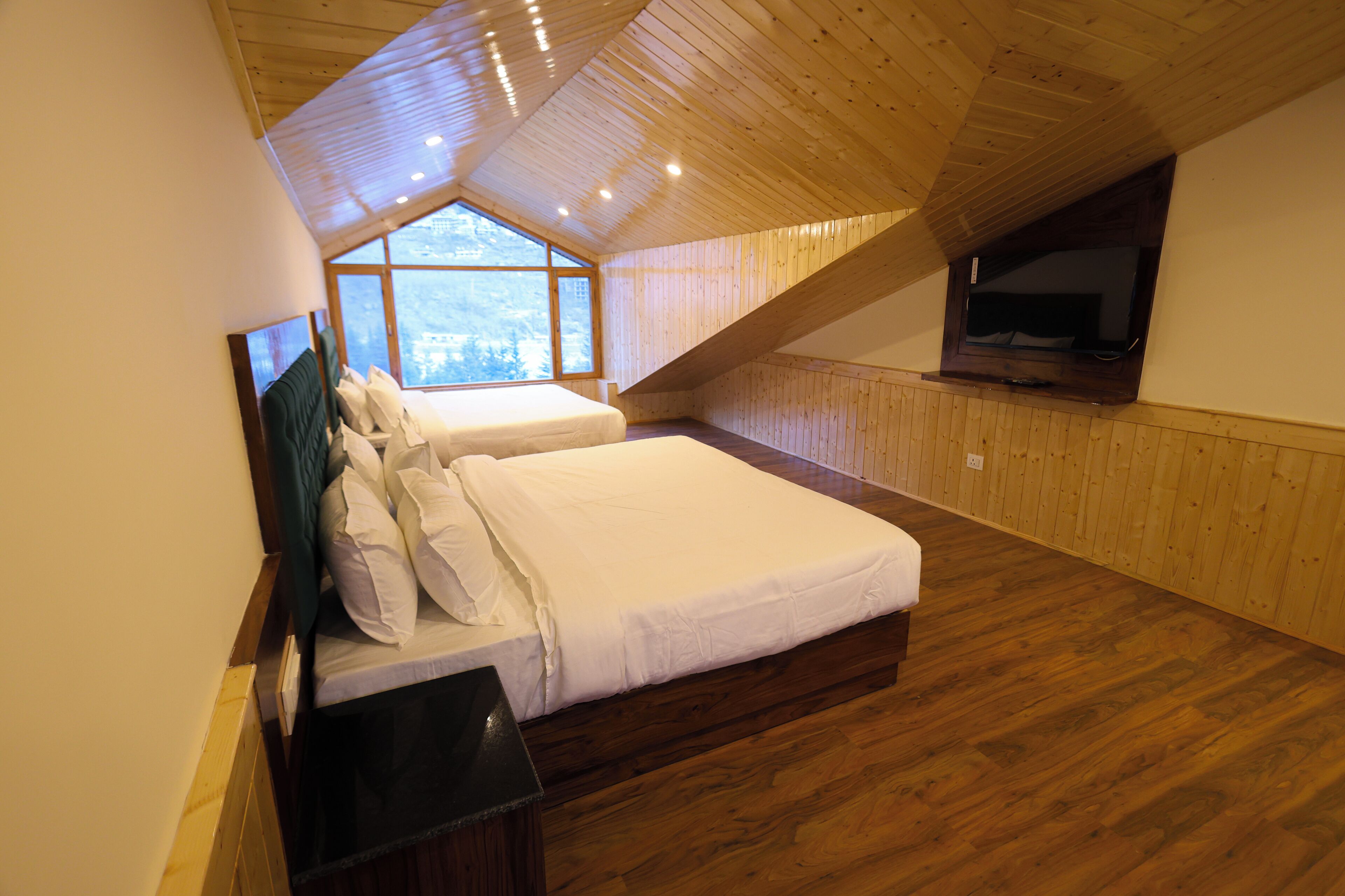 A bedroom with a wooden ceiling, a large window, and a bed with white bedding.
