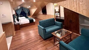 Una habitación acogedora con pisos de madera, una cama con cortinas azules, un sofá azul y una mesita.