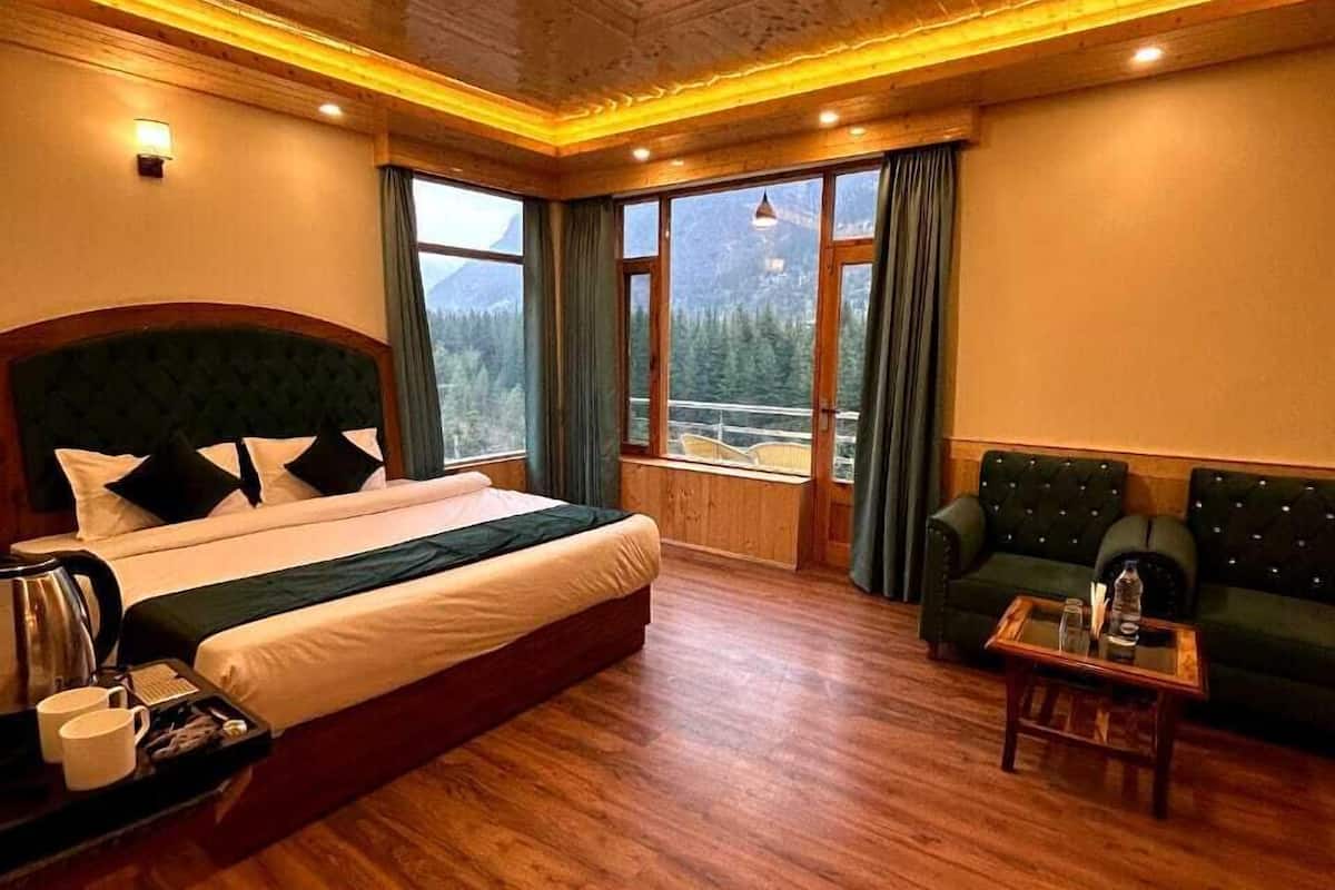 Un'ampia camera da letto con un letto grande, un divano e vista sulle montagne dalle finestre.