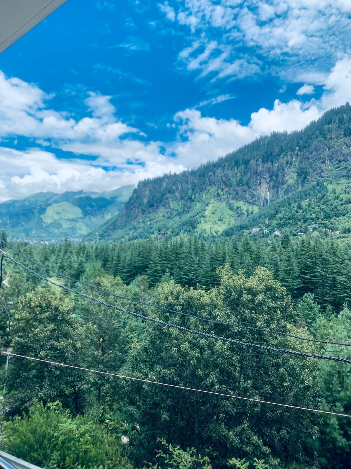 A mountainous landscape with dense forests and a clear blue sky.