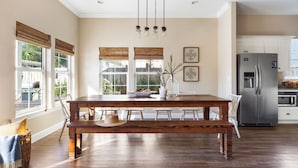 A spacious kitchen with a large wooden table, white cabinets, and a stainless steel refrigerator. - Sleeps 18! Private Pool, Hot Tub, Near Beach | Miramar Dream House by AvantStay (Miramar Beach)