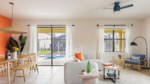A spacious living room with a dining area, a sofa, a coffee table, and a view of a swimming pool.