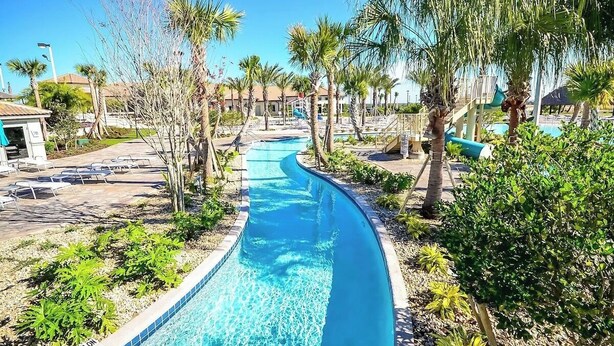 A pool area with a clear water path, surrounded by palm trees and lounge chairs.