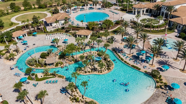 Vista aérea de un complejo turístico con múltiples piscinas, palmeras y zonas de descanso.